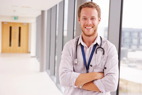 Doctor smiling and standing near a window