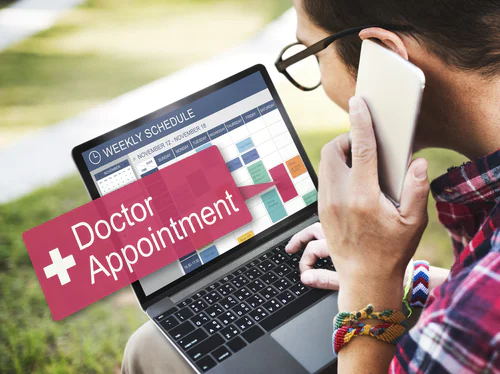 Person on phone looking at laptop with a doctor appointment alert