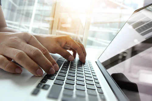 Two hands typing on a laptop keyboard