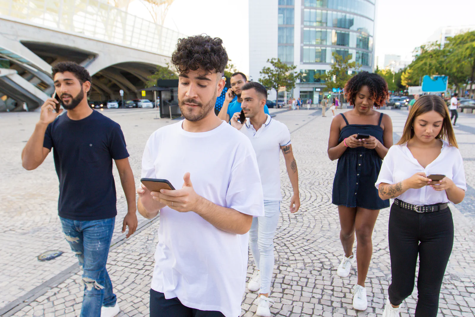 Group of people with smartphones walking down city street Group of people with smartphones walking down city street. Young mix raced men and woman walking outside, talking on cells, using mobile phones. Digital communication concept